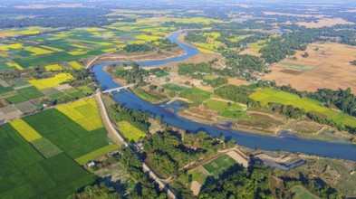 An aerial view reveals a gently curving river winding through the countryside, its silvery surface