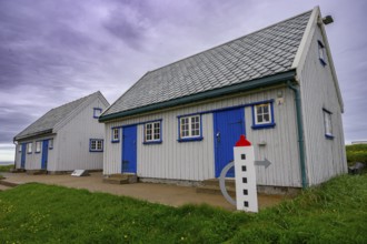 An old grey lighthouse dictionary house with a sloping roof at Kjølnes Fyr, small windows and