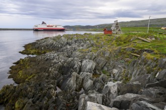 The Hurtigrouten Hurtigruten ship Kong Harald arrives at Berlevag harbour, on the horizon with a
