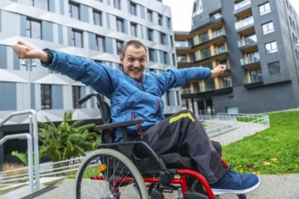 Smiling man in a wheelchair with arms outstretched expressing joy and freedom while navigating an