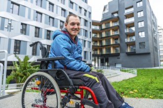 Smiling man with a disability navigating a modern urban environment in his wheelchair, highlighting