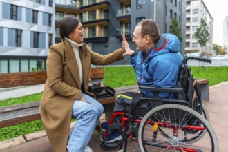 Smiling woman and man with a physical disability celebrating with a high five, reflecting themes of