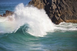 Waves crash against rocks at the mainland's easternmost point, creating rainbows in the ocean spray