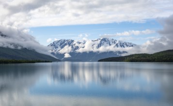 Snowy mountains in spring are reflected in turquoise blue Kenai Lake, Cooper Landing, Kenai