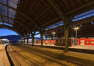 Empty platform with the two-nave platform hall and regional express in the evening, central railway