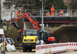 Construction workers with construction machinery on a railway bridge construction site,