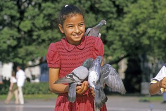 A girl holding two doves and feeding them, Placa de Catalunya, Barcelona, Spain, June 1999,