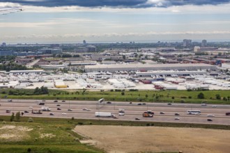 An industrial cityscape with a busy highway and overlying clouds, view from an airplane of the