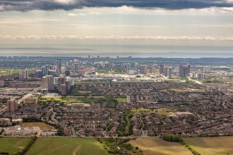 A comprehensive panorama of a city with high-rise buildings and suburbs under a cloudy sky, near