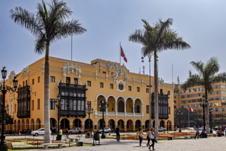 Colonial building with arches and national flag, surrounded by palm trees, in a sunny square, The
