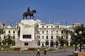 Equestrian statue on a large pedestal in front of an imposing historic building under a blue sky,