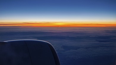 Sunset with dark sky and aircraft engine, On a plane above the clouds