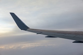 Close-up of airplane wing against grey sky, On an airplane above the clouds