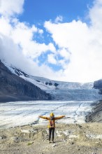 Female hiker with backpack and yellow jacket is enjoying the breathtaking view of the athabasca