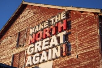 Red fishing building with the inscription Make the North great again at Vardö harbour, Vardø,