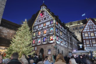 Christmassy illuminated square with the historic Pilate House with advent calendar, in the evening