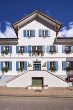 Town Hall, façade with windows and shutters, flower boxes, double stairway, blue sky, cumulus