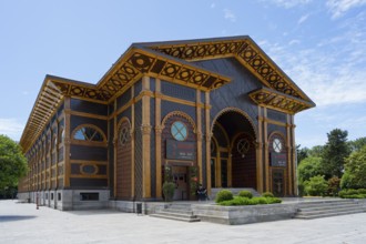 Decorated wooden building with decorative elements and an inviting entrance under a blue sky,