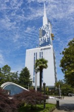 State-of-the-art building in the municipal park with palm trees against a blue sky, Batumi Tower