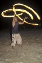 A man waves burning torches on the beach of Coral Beach Resort on the island of Ko Lanta, Thailand,