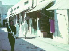 Policeman standing in street of small shops in souk of old town medina, Tripoli, Libya, North