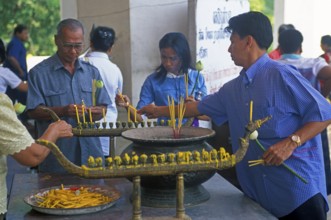 Believers light candles in front of the temple with the Buddha statue Phra Mongkhonbophit,