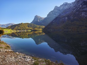 Autumn-colored forest is reflected in Obersee, Näfels, Canton of Glarus, Switzerland