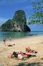 Rocks in the sea, people and longtail boats on Pranang Cave beach, two years in front of the