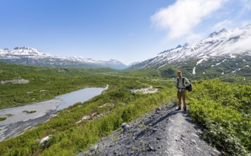 Hikers on glacial moraine, view of the vast Tsina River valley with mountains, Worthington Glacier