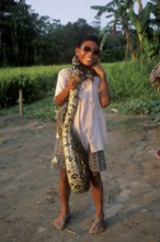 A boy whose father runs a small private zoo near Iquitos on the Amazon shows a boa, Peru, South