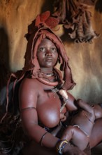 Himba woman sitting with baby in traditional hut, Himba village, Kaokoveld, Kunene, Namibia