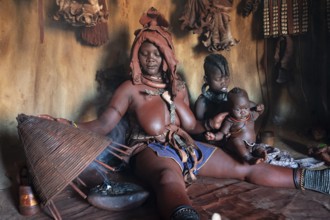 Himba woman sitting with baby, Himba perfume, scented smoke from burning plants, Himba village,