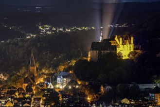 Castle and church shine in night lighting on a wooded hill. The Landgrave's Castle of Marburg in