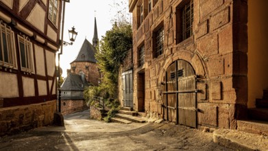 Historic old town alleyway with half-timbered houses and church in the warm light of sunset, The