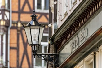 Nostalgic lantern next to a building in front of half-timbered buildings and windows in urban
