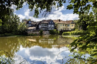 Half-timbered houses on the lakeside with blue sky and clouds, surrounded by trees, The historic