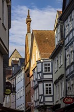 Picturesque old town street with half-timbered houses and business signs in sunlight, The historic