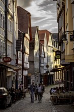 A lively street scene at sunset with people sitting at cafés in the old town, The historic old town