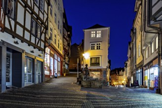 Night view of an old town street with illuminated facades and cobblestones, At the blue hour in the