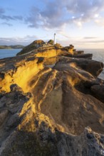 Castlepoint lighthouse on a rock, sea, sunrise. Castlepoint, Wairarapa Coast, Wellington Region,