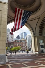 American flag fluttering, distinctive archway, Boston Harbor Hotel, Rowes Wharf, passers-by,
