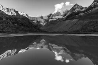 The Moiry glacier and mountain peaks are reflected in Lac de Chateaupre, black and white photo, Val
