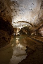 Stalactites and stalagmites, reflection in a small underground lake, rock formations in a
