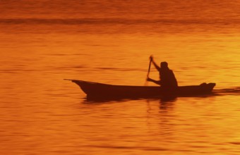 Silhouette of a fisherman in his boat at sunrise near Mikadi Beach, Dar es-Salaam, Tanzania,