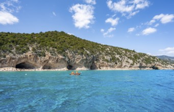 Kayakers in clear blue water, picturesque rocky coast, cliffs and Cala Luna beach, Golfo di Orosei,