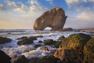 Penedo do Guincho, a large boulder rock arch at Praia da Santa Cruz, Portugal, with ocean waves and