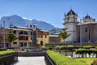 A square with a church against a mountain backdrop in sunny weather and clear skies, the town of