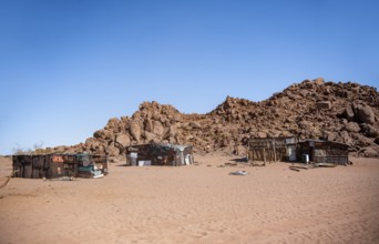 Simple poor huts made of corrugated iron and wood, desert landscape, barren landscape with hills of