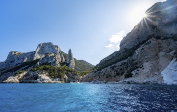 Picturesque rocky coast, cliffs with L'Aguglia pinnacle, blue sea and Cala Goloritzé beach, sun