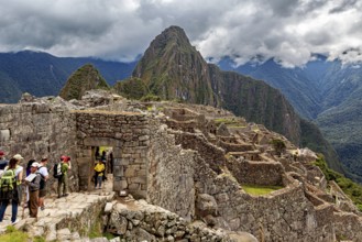 Visitors enter the ancient ruins of Machu Picchu under cloudy skies, The ruins of the Inca city of